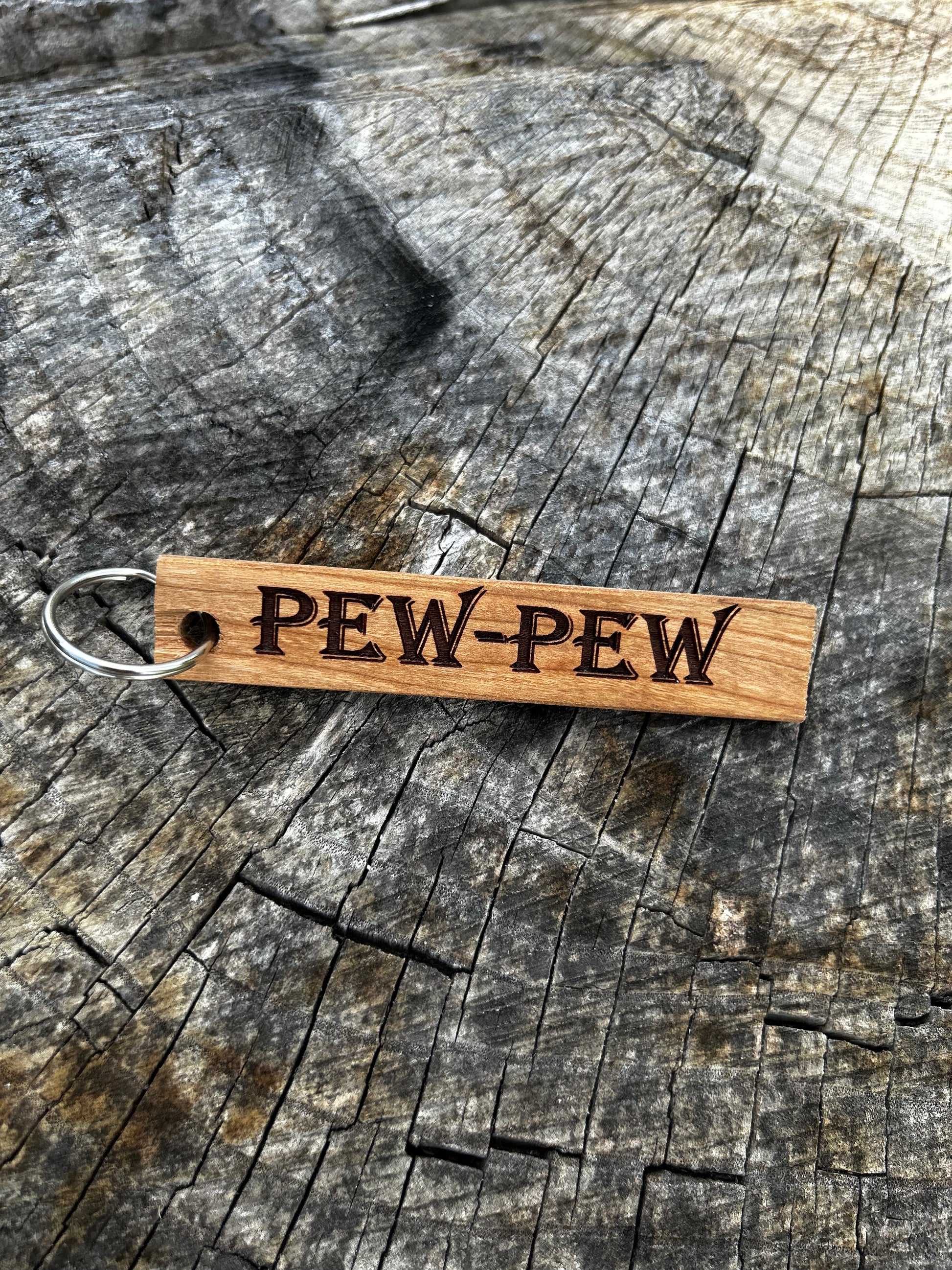 Textured Wooden Keychain with the word "Pew-Pew" and the Oakley Nerd Nook logo pressed into it