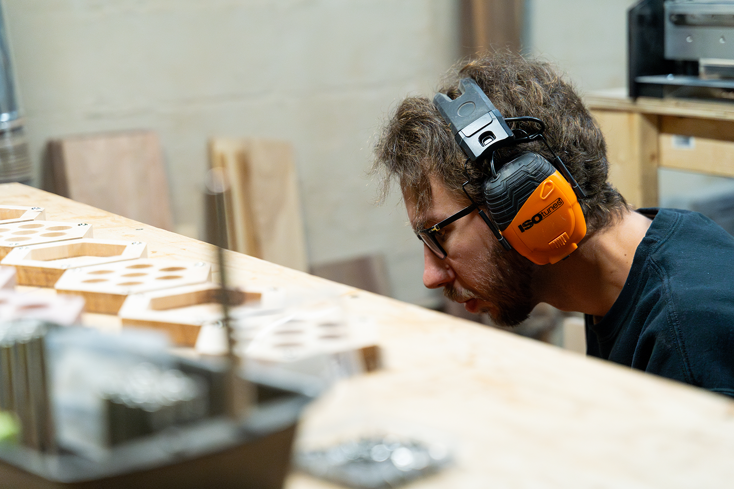 Over the table shot of Oakley kneeling down working on sanding Click-Clack Haversacks