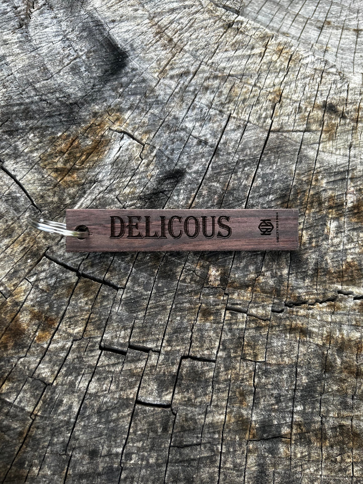 Willow Wooden Keychain with the word "Delicious" and the Oakley Nerd Nook logo pressed into it