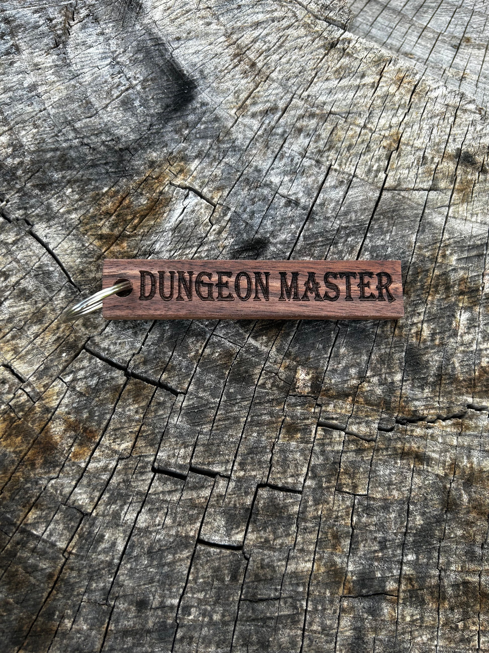 Willow Wooden Keychain with the word "Dungeon Master" and the Oakley Nerd Nook logo pressed into it