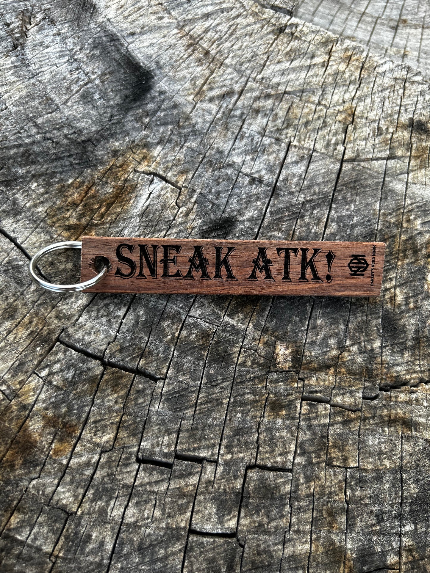 Willow Wooden Keychain with the word "Sneak Atk!" and the Oakley Nerd Nook logo pressed into it